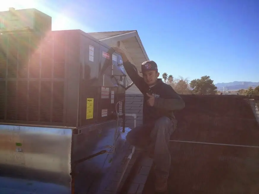 HVAC technician performing Heat Pump Repair on a rooftop unit in Portales
